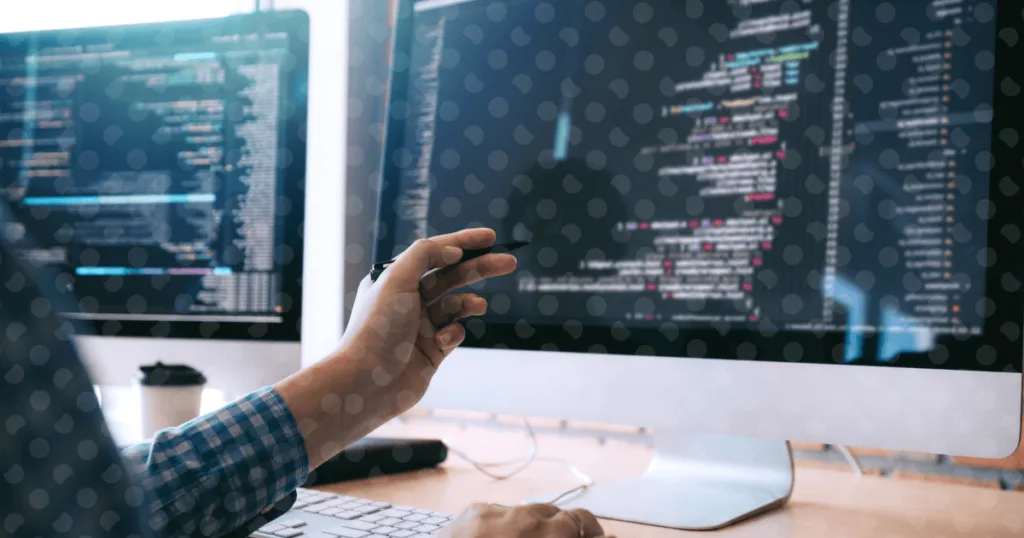 Persona davanti a un computer indica lo schermo che mostra linee di codice